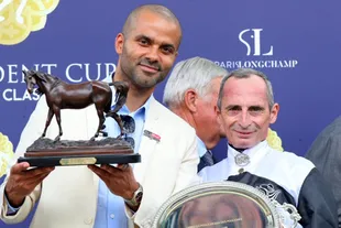 Manu Ginóbili's former teammate shows off the winning trophy for his filly Mangoustine; next to him, jockey Gerald Mosse.